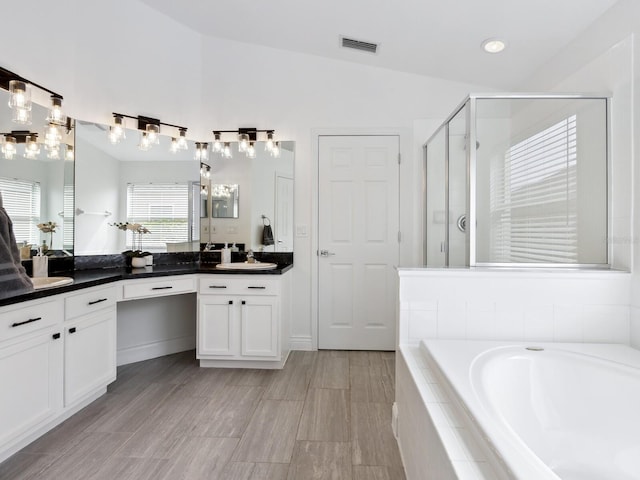 bathroom featuring vaulted ceiling, vanity, and plus walk in shower