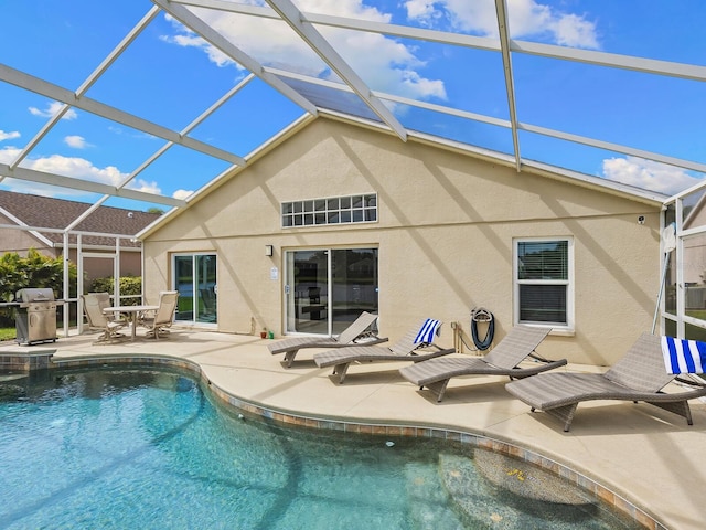 view of pool featuring glass enclosure, a grill, and a patio area