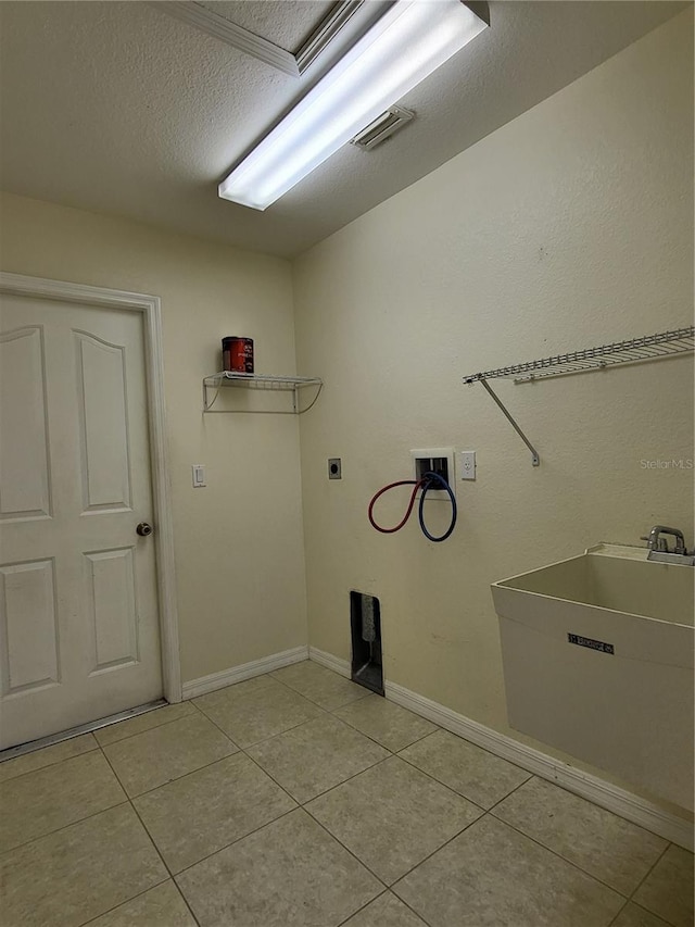 washroom with sink, electric dryer hookup, hookup for a washing machine, a textured ceiling, and light tile patterned floors