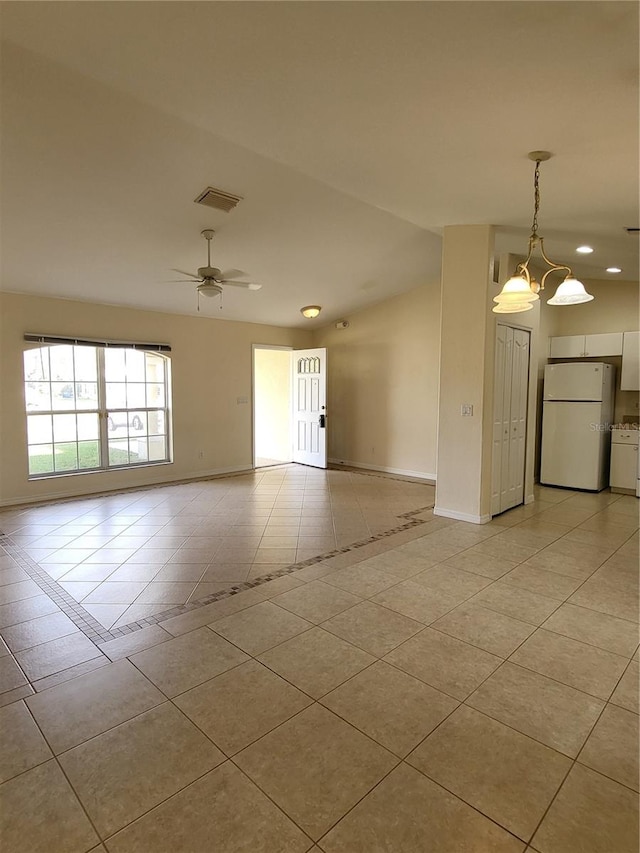 unfurnished room featuring ceiling fan with notable chandelier, light tile patterned floors, and vaulted ceiling