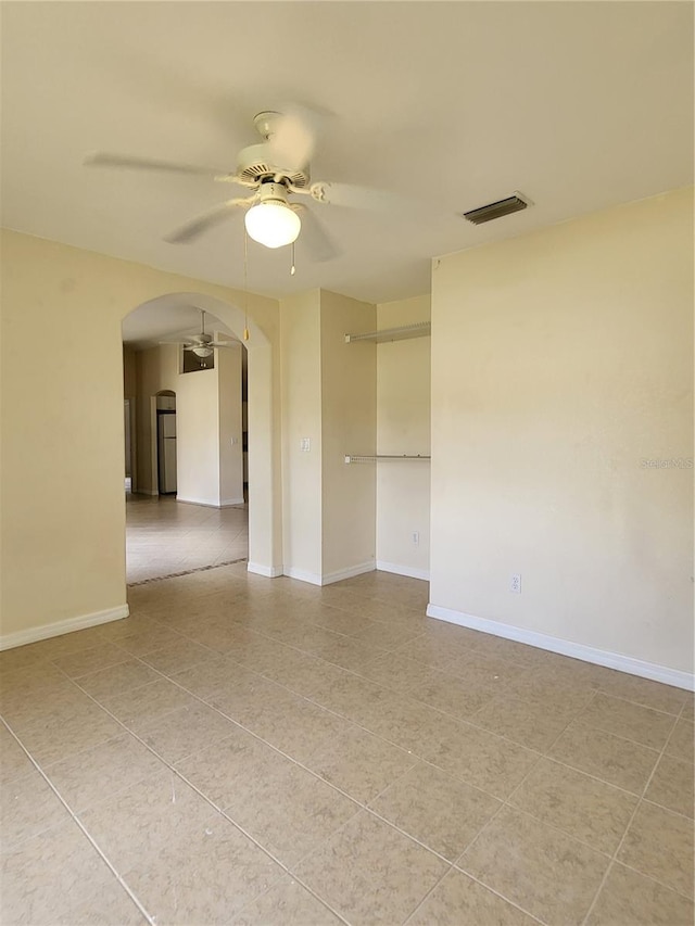 tiled spare room featuring ceiling fan