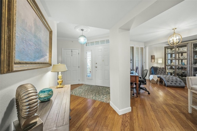 entrance foyer with hardwood / wood-style floors, crown molding, and a notable chandelier