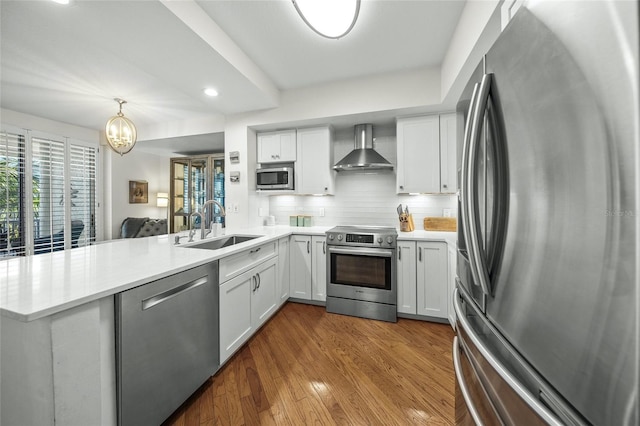 kitchen with white cabinetry, stainless steel appliances, kitchen peninsula, and wall chimney exhaust hood