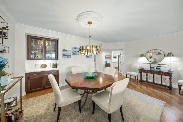 dining area featuring crown molding, a chandelier, and light wood-type flooring