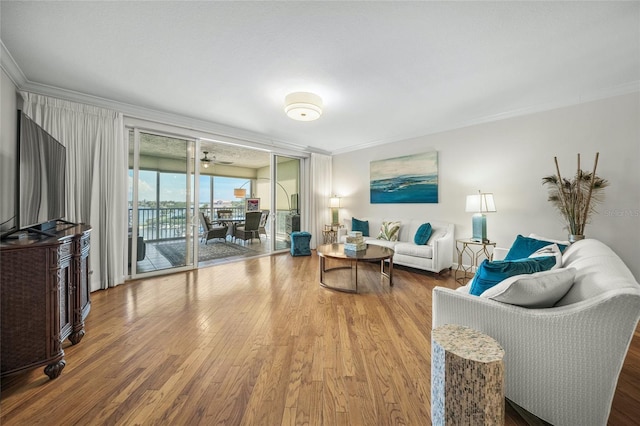 living room featuring wood-type flooring, ornamental molding, and a wall of windows