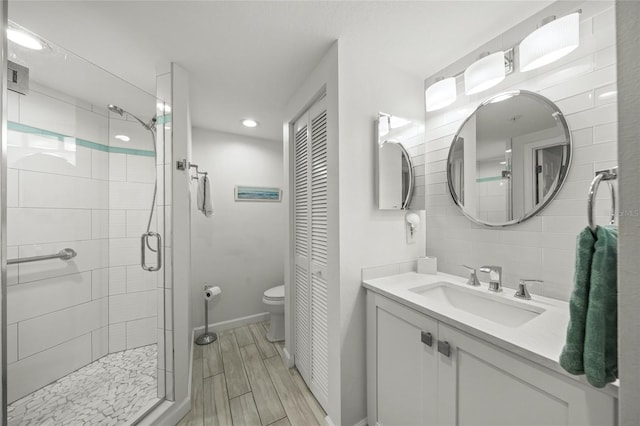 bathroom with vanity, a shower with door, and toilet