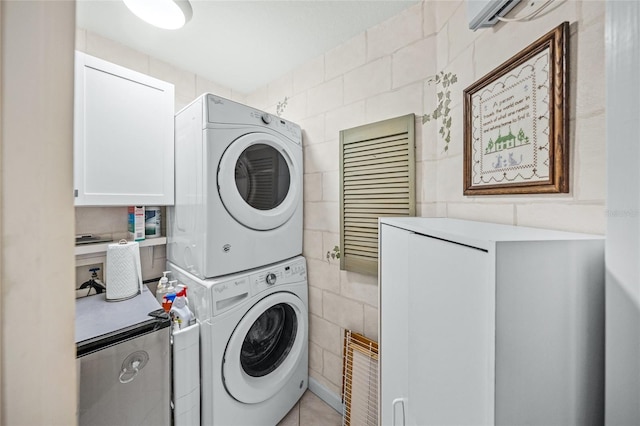 laundry area with cabinets, stacked washer / dryer, and tile walls