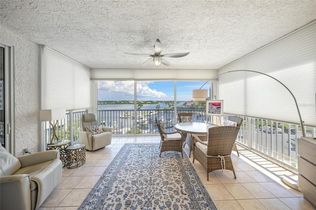 sunroom with a water view and ceiling fan