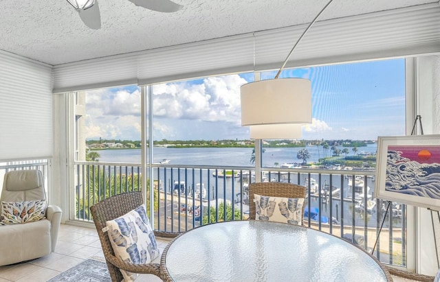 sunroom / solarium featuring plenty of natural light, ceiling fan, and a water view