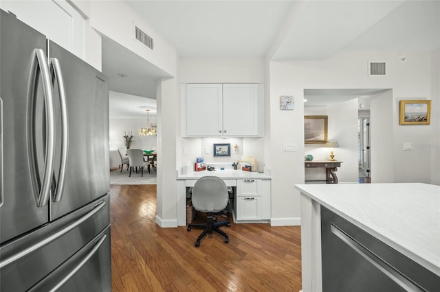 kitchen featuring white cabinetry, dark wood-type flooring, stainless steel fridge, and an inviting chandelier