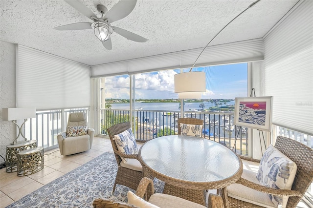 sunroom featuring a water view and ceiling fan