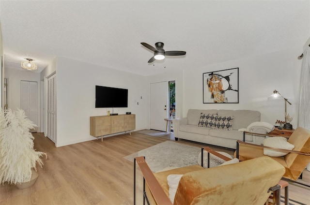 living room with ceiling fan, a textured ceiling, and light hardwood / wood-style floors