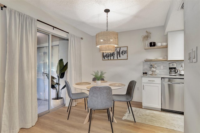 dining room featuring light wood-type flooring, a textured ceiling, and a chandelier