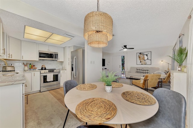 dining room featuring light hardwood / wood-style flooring, a textured ceiling, ceiling fan with notable chandelier, and sink