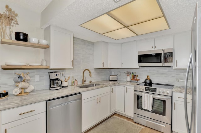 kitchen featuring backsplash, sink, stainless steel appliances, and white cabinets