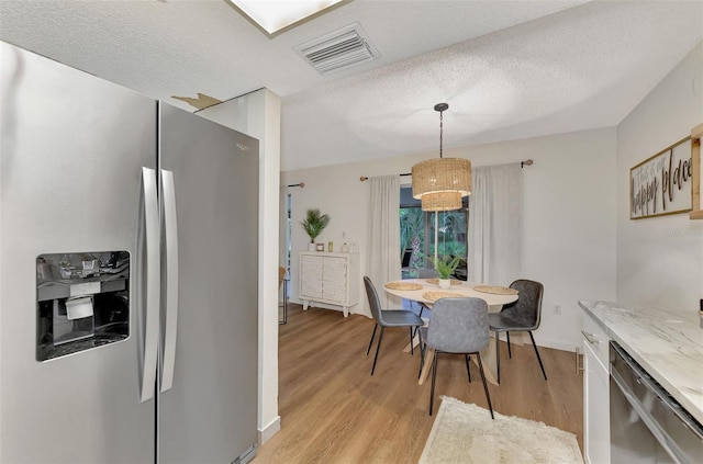 dining space featuring a textured ceiling and light hardwood / wood-style flooring