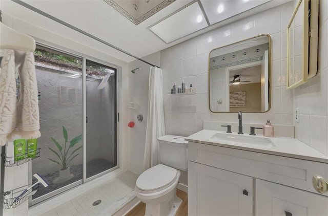 bathroom with tile walls, vanity, ceiling fan, toilet, and a shower with curtain