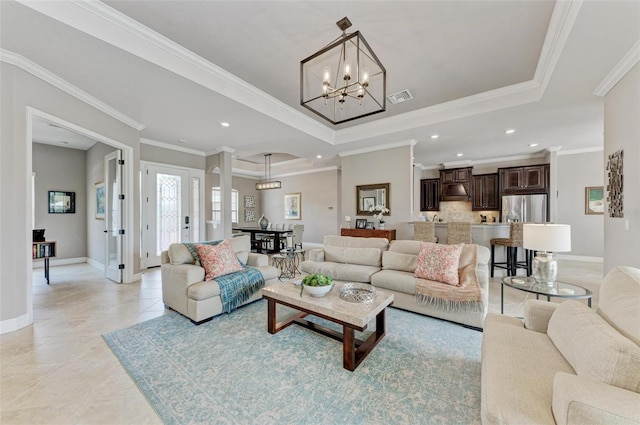 living room featuring a raised ceiling, crown molding, and a chandelier