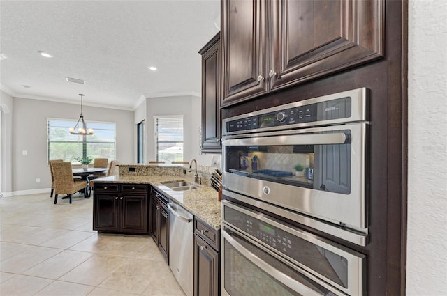 kitchen with sink, ornamental molding, a textured ceiling, appliances with stainless steel finishes, and light stone countertops