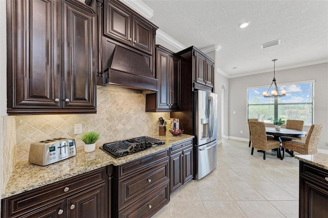 kitchen featuring custom exhaust hood, stainless steel fridge, decorative light fixtures, black gas stovetop, and crown molding