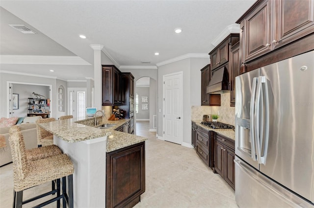 kitchen with a breakfast bar area, stainless steel appliances, premium range hood, ornamental molding, and sink