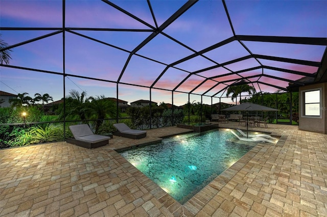 pool at dusk with a lanai and a patio area