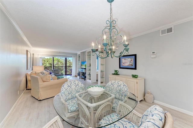 dining room featuring a textured ceiling, an inviting chandelier, light wood-type flooring, and ornamental molding