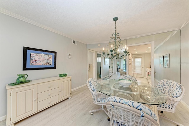 dining space with crown molding, a notable chandelier, a textured ceiling, and light hardwood / wood-style floors