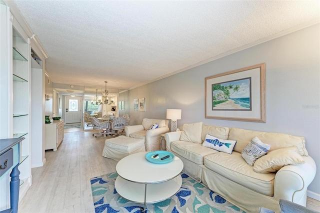 living room featuring light hardwood / wood-style floors, crown molding, a textured ceiling, and a chandelier