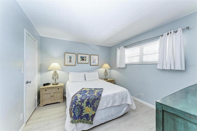 bedroom with a textured ceiling and light wood-type flooring