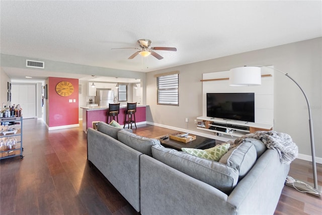 living room with a textured ceiling, dark hardwood / wood-style floors, and ceiling fan