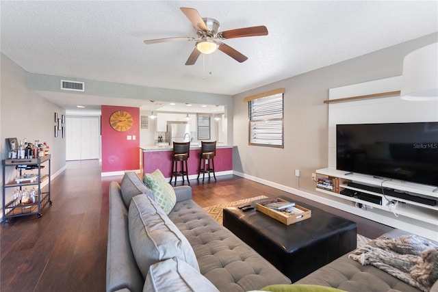 living room featuring a textured ceiling, dark hardwood / wood-style flooring, and ceiling fan