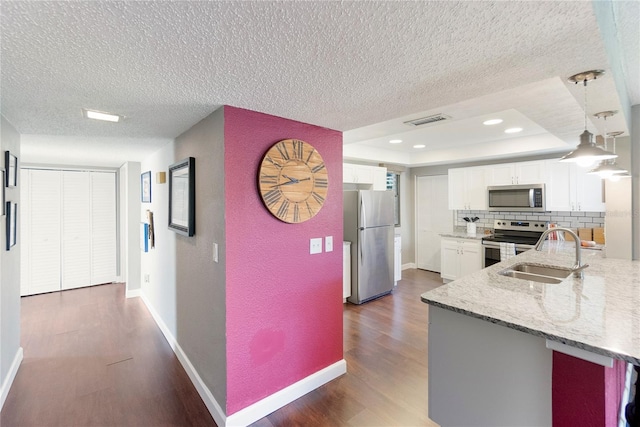 kitchen with light stone counters, dark wood-type flooring, stainless steel appliances, and white cabinets