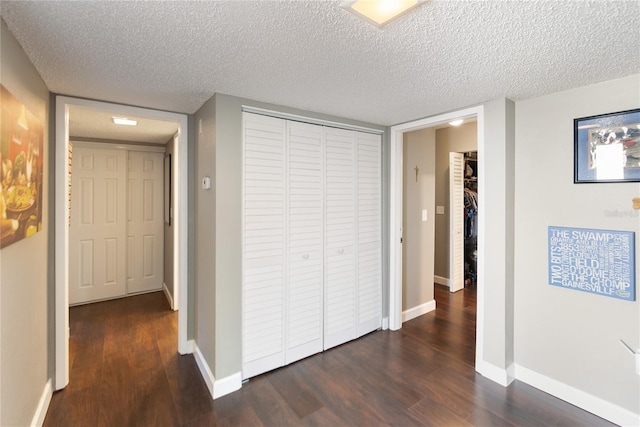 hallway with a textured ceiling and dark hardwood / wood-style floors