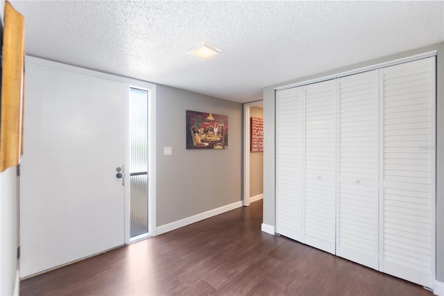 unfurnished bedroom with a closet, a textured ceiling, and dark hardwood / wood-style flooring