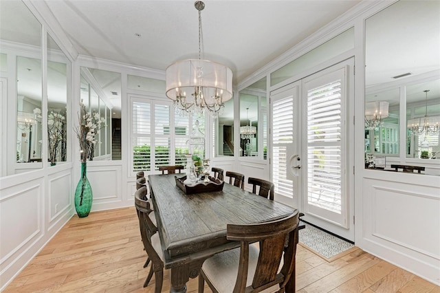 dining area with an inviting chandelier, light hardwood / wood-style flooring, ornamental molding, and a wealth of natural light