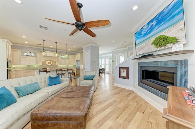 living room featuring light hardwood / wood-style floors, ornamental molding, and ceiling fan