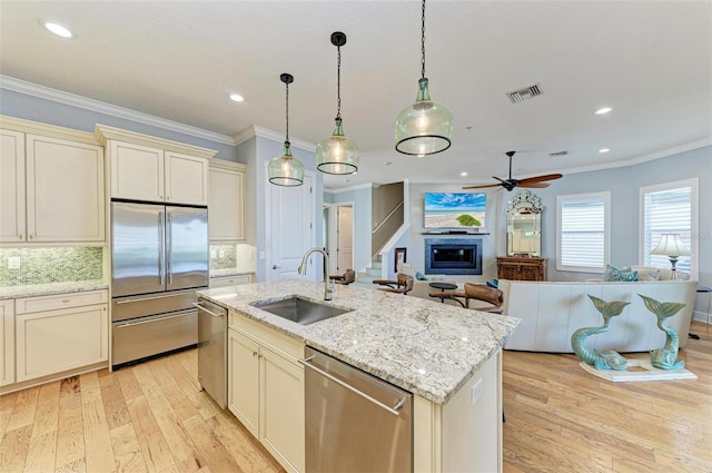 kitchen with stainless steel appliances, cream cabinets, ceiling fan, and sink