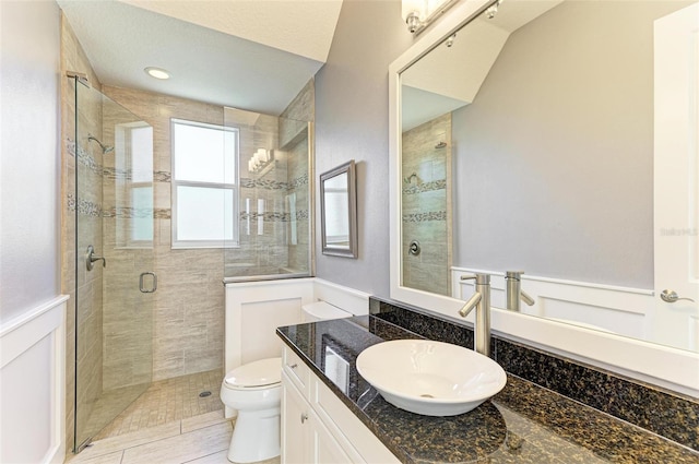 bathroom featuring a textured ceiling, an enclosed shower, vanity, and toilet