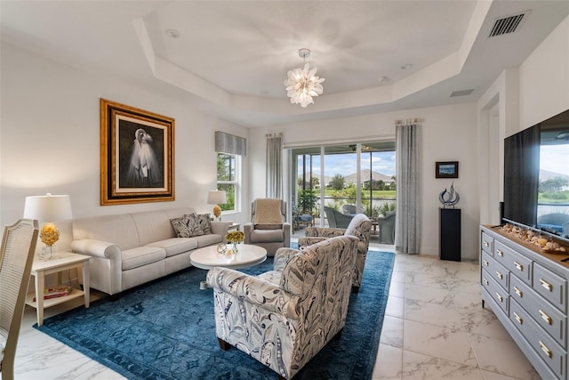 living room with a chandelier, a tray ceiling, and a wealth of natural light