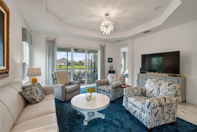 living room featuring a raised ceiling and a chandelier