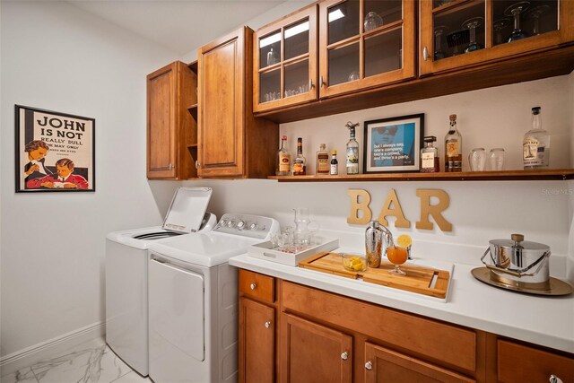 laundry area with washing machine and dryer, cabinets, and bar area