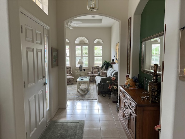 foyer featuring ceiling fan, light tile patterned floors, and a healthy amount of sunlight