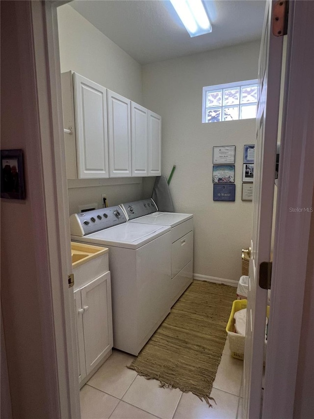 laundry room with cabinets, washing machine and clothes dryer, and light tile patterned flooring