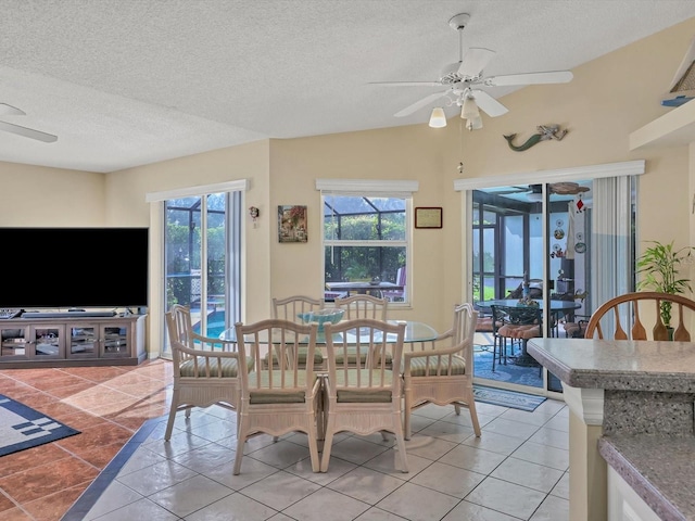 tiled dining space featuring ceiling fan, lofted ceiling, and a textured ceiling