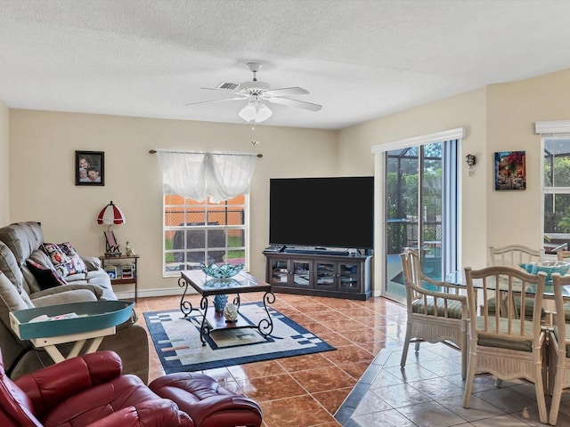 living room featuring tile patterned floors, ceiling fan, and a textured ceiling