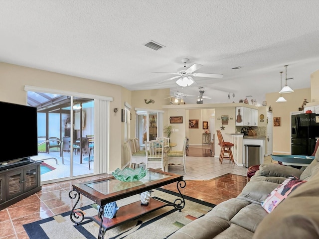 tiled living room featuring ceiling fan and a textured ceiling