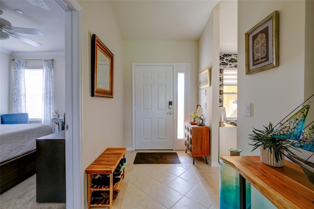 tiled foyer with ornamental molding and ceiling fan