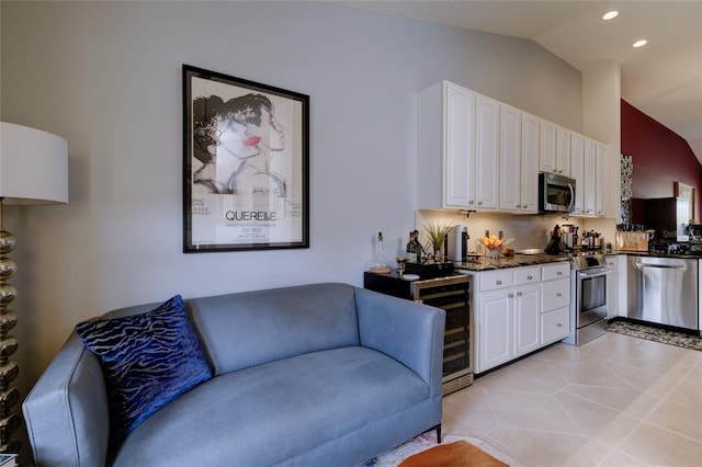 kitchen with white cabinets, light tile patterned floors, backsplash, stainless steel appliances, and vaulted ceiling