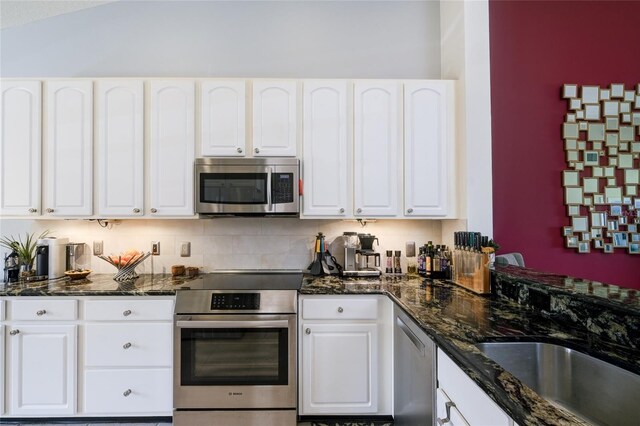 kitchen featuring appliances with stainless steel finishes, dark stone countertops, and white cabinets